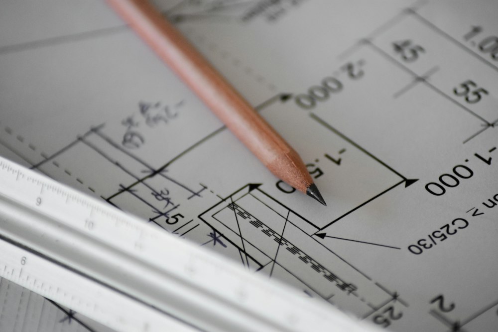 A pencil resting on a dimensioned working drawing